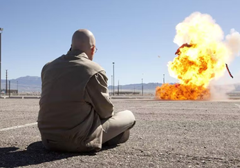Walter White sitting cross legged watching a giant explosion